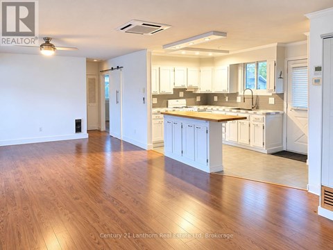 A spacious kitchen with white cabinets and a wooden floor.