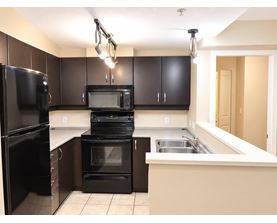 A kitchen with black appliances and brown cabinets.