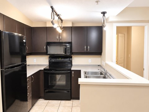 A kitchen with black appliances and brown cabinets.