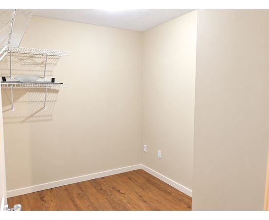 Empty room with a shelf and a wooden floor.