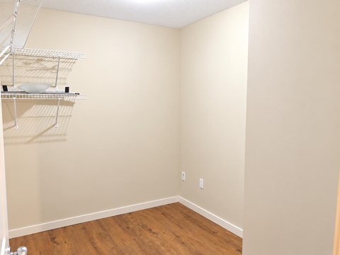 Empty room with a shelf and a wooden floor.