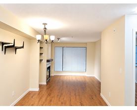 A spacious room with wooden floors and a chandelier.
