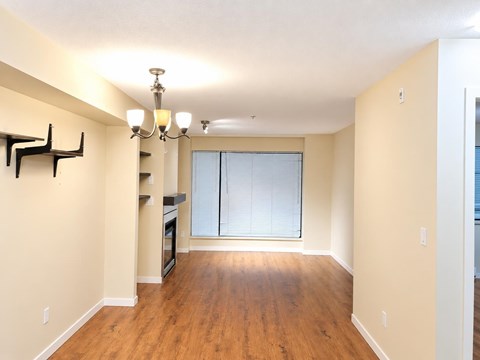 A spacious room with wooden floors and a chandelier.