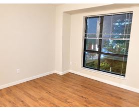 A room with a window showing a view of a building and trees outside.