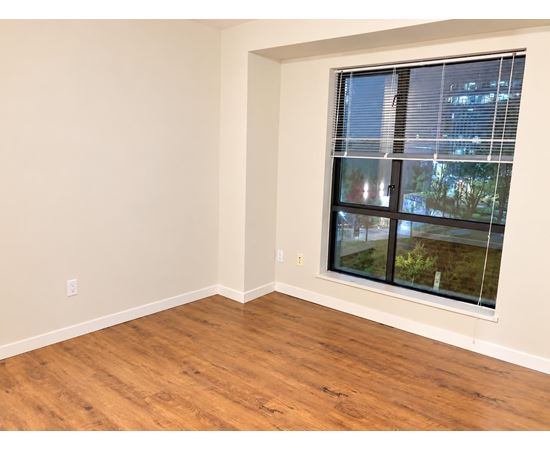 A room with a window showing a view of a building and trees outside.