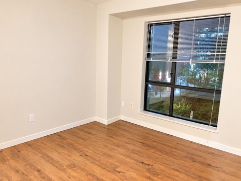 A room with a window showing a view of a building and trees outside.