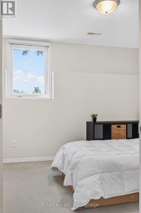 A bedroom with a bed, nightstand, and window.