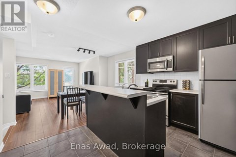 A modern kitchen with black cabinets and stainless steel appliances.
