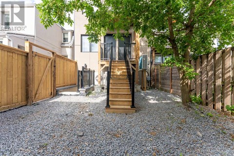 A gravel driveway leads to a wooden staircase and a house.