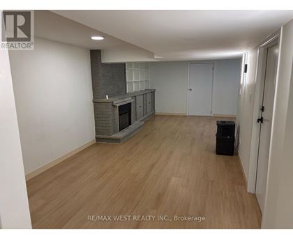 A spacious room with a fireplace and wooden flooring.