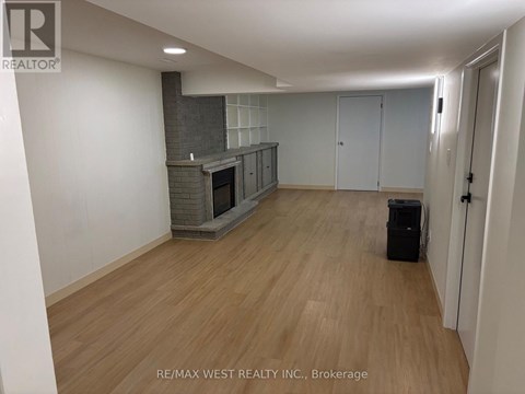 A spacious room with a fireplace and wooden flooring.