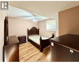 A bedroom with a large bed and wooden flooring.