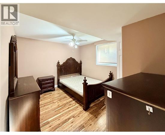 A bedroom with a large bed and wooden flooring.