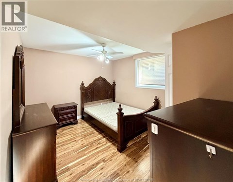 A bedroom with a large bed and wooden flooring.