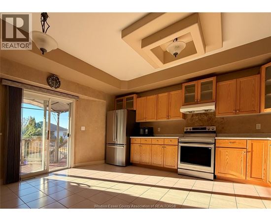 A kitchen with wooden cabinets and a stainless steel refrigerator.