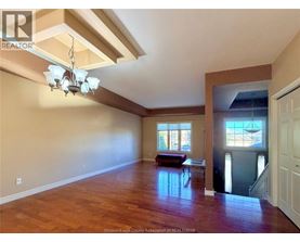 A large empty room with wooden floors and a chandelier.