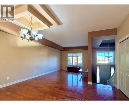 A large empty room with wooden floors and a chandelier.