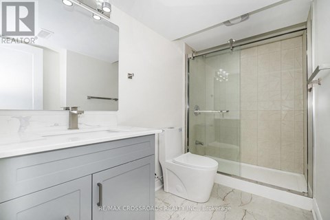 A white toilet sits in a bathroom with a glass shower door.