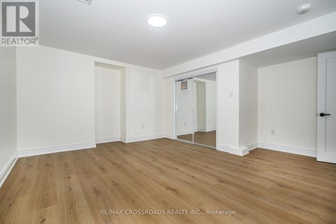 A spacious room with wooden flooring and white walls.