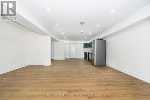 A spacious room with wooden flooring and white walls.