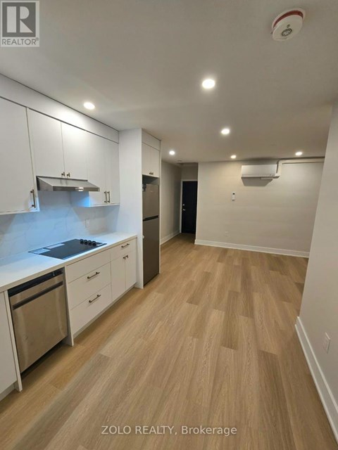 A kitchen with white cabinets and a wooden floor.