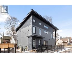 A modern house with a grey exterior and a black fence in front.