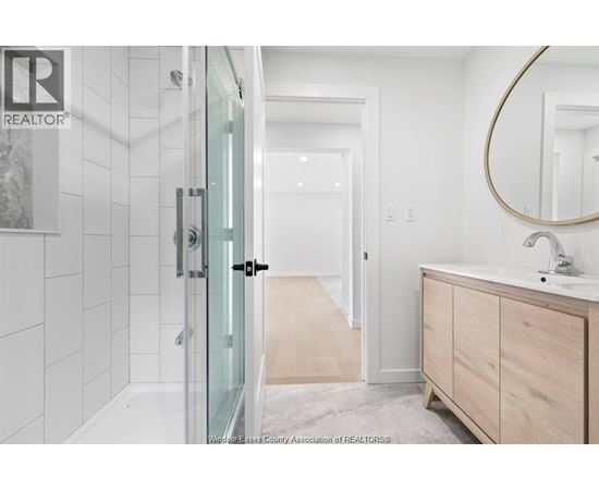 A bathroom with a glass shower door and a wooden vanity.