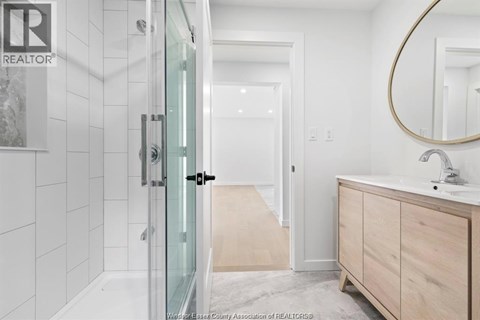 A bathroom with a glass shower door and a wooden vanity.