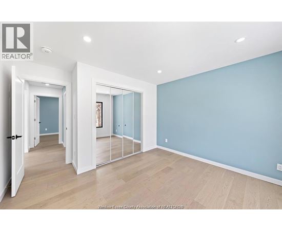 A spacious room with light blue walls and wooden flooring.