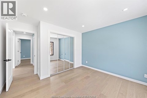 A spacious room with light blue walls and wooden flooring.