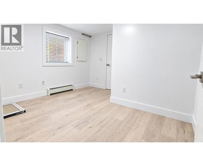 A room with a wooden floor and a window with blinds.