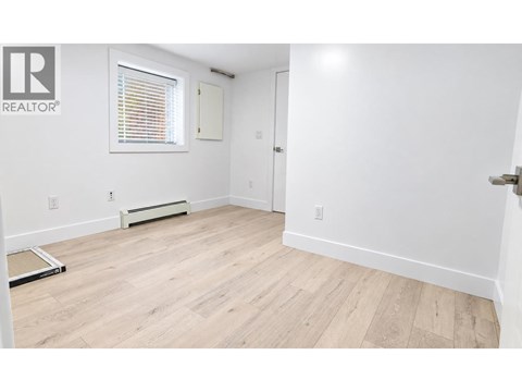 A room with a wooden floor and a window with blinds.