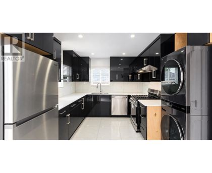 A modern kitchen with black cabinets and stainless steel appliances.