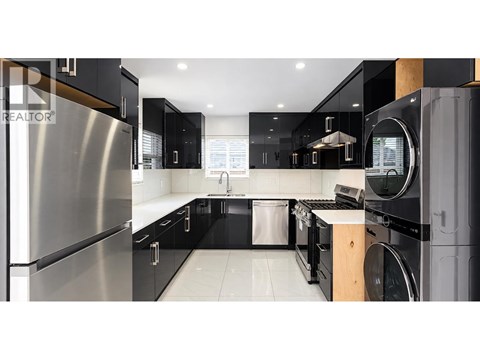 A modern kitchen with black cabinets and stainless steel appliances.