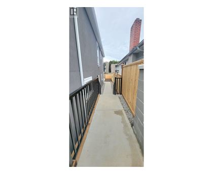 A concrete walkway leads to a building with a red chimney.