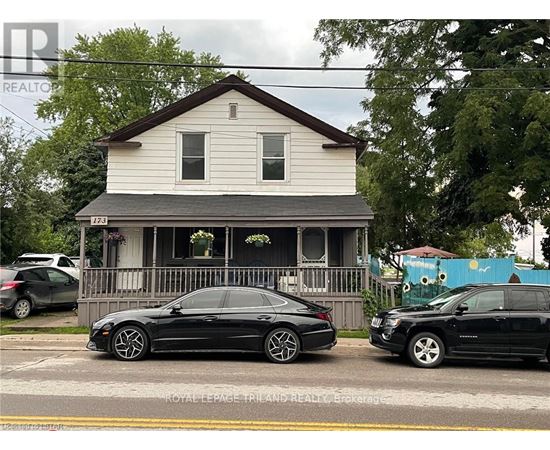 A black car is parked in front of a white house.