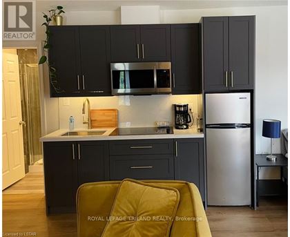 A kitchen with black cabinets and a stainless steel refrigerator.