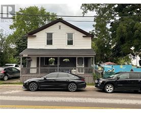 A black car is parked in front of a white house.