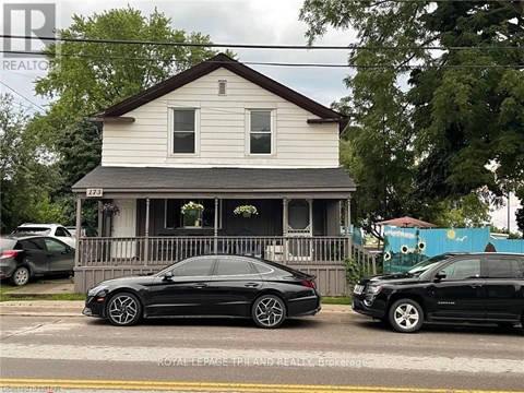 A black car is parked in front of a white house.