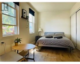 A bedroom with a bed, nightstand, and a table with a plant on it.