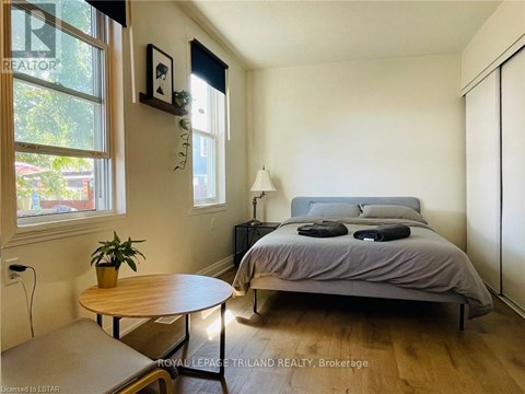 A bedroom with a bed, nightstand, and a table with a plant on it.