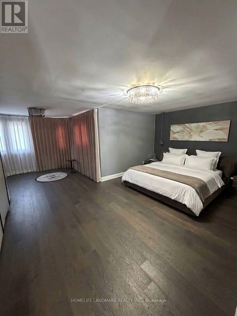 A bedroom with a bed, a chandelier, and a window with curtains.