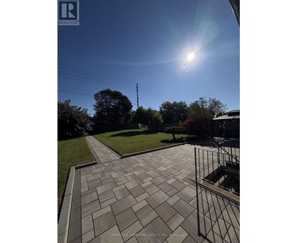 A sunny day with a clear blue sky and a pathway leading to a grassy area.