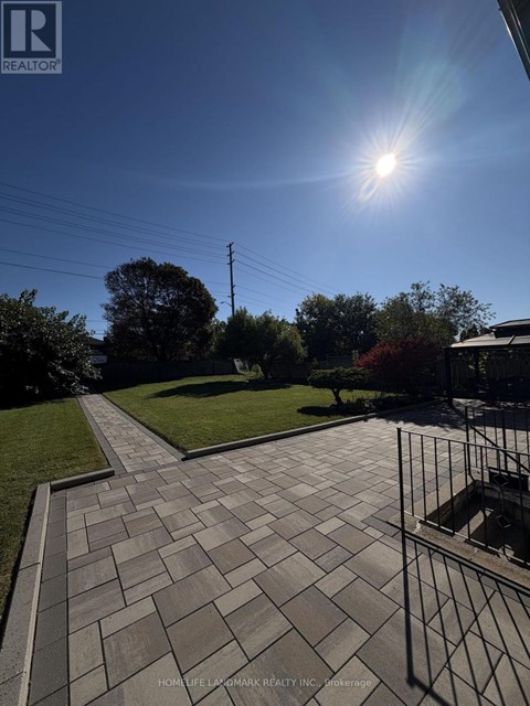 A sunny day with a clear blue sky and a pathway leading to a grassy area.