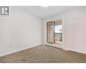 A room with a carpeted floor and a sliding glass door leading to a balcony.