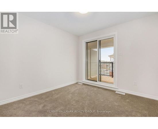 A room with a carpeted floor and a sliding glass door leading to a balcony.