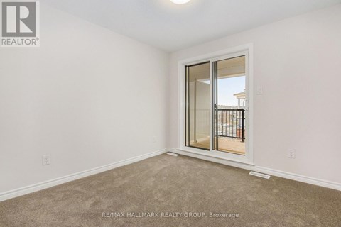A room with a carpeted floor and a sliding glass door leading to a balcony.