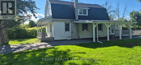 A house with a porch and a sign that says "EKORT REALTY TD Brokerage".