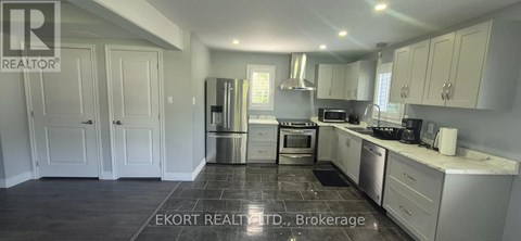 A kitchen with white cabinets and a black floor.