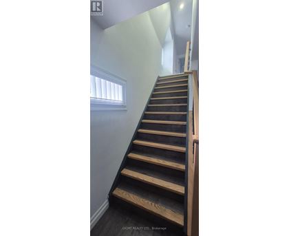 A wooden staircase with a white wall and a window.